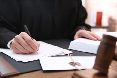 Photo of Judge working with papers at table in office, closeup. Law and justice concept