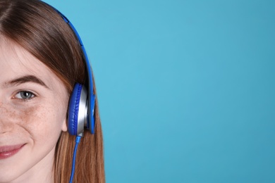 Teenage girl enjoying music in headphones on color background, closeup. Space for text
