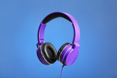 Stylish headphones with pads on color background