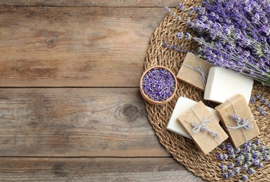 Flat lay composition of handmade soap bars with lavender flowers on brown wooden background. Space for text