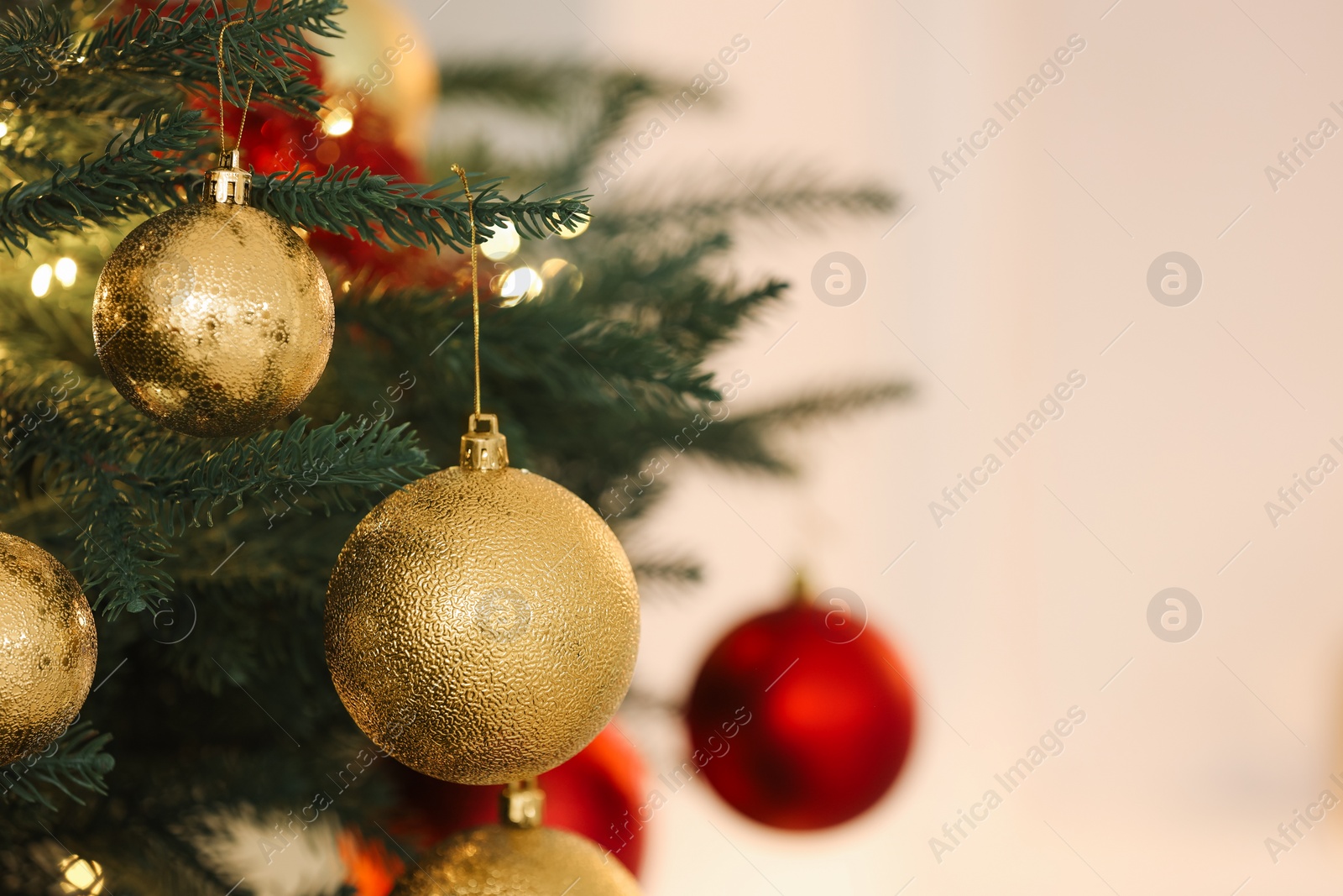 Photo of Christmas tree decorated with festive balls on light background, closeup. Space for text