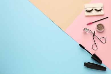 Photo of Flat lay composition with eyelash curler, makeup products and accessories on color background. Space for text