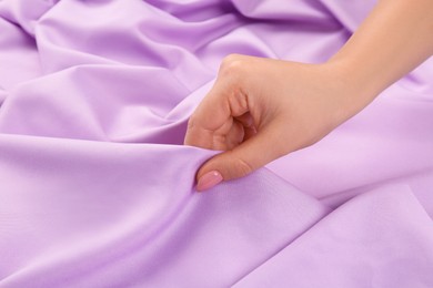 Photo of Woman touching delicate violet fabric, closeup view