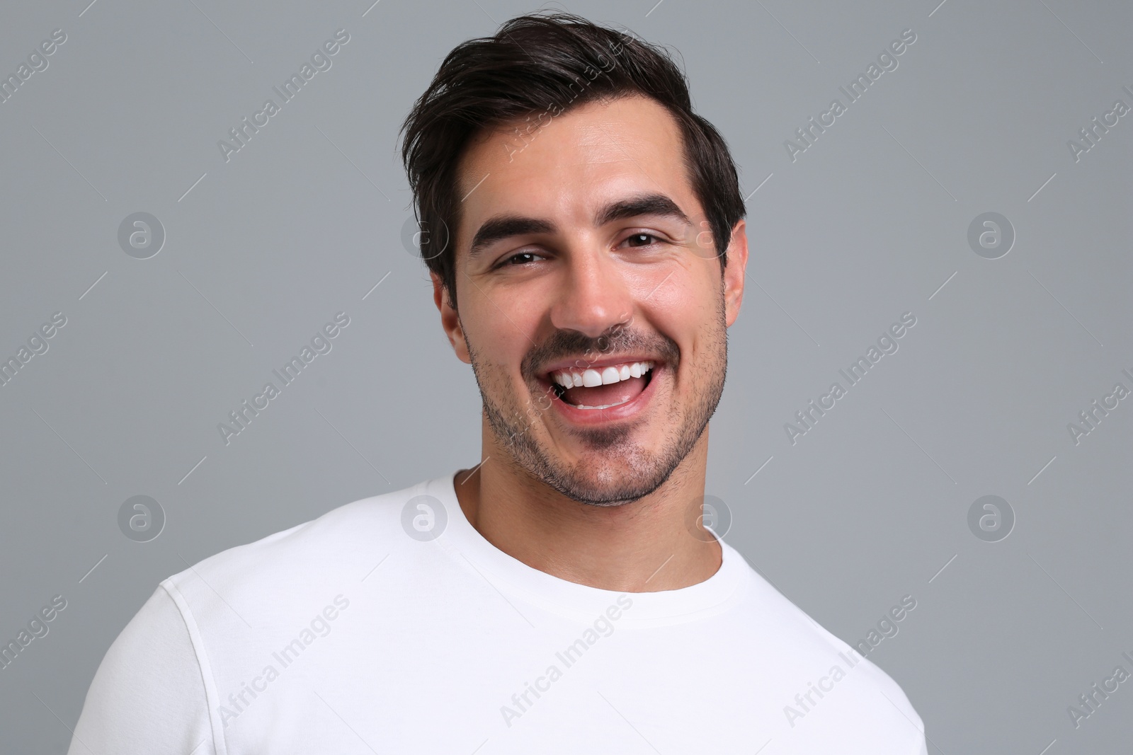 Photo of Portrait of handsome young man in white t-shirt on grey background