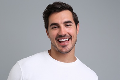 Portrait of handsome young man in white t-shirt on grey background