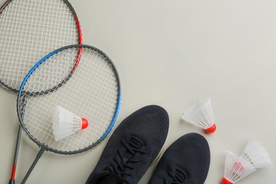 Photo of Badminton rackets, shuttlecocks and shoes on light grey background, flat lay. Space for text