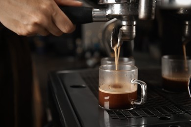 Barista making espresso using professional coffee machine, closeup