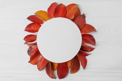 Flat lay composition with blank card and autumn leaves on white wooden table. Space for text