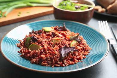 Photo of Tasty brown rice with vegetables on table, closeup