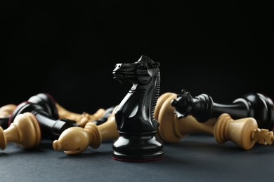 Photo of Black knight among fallen chess pieces on dark background