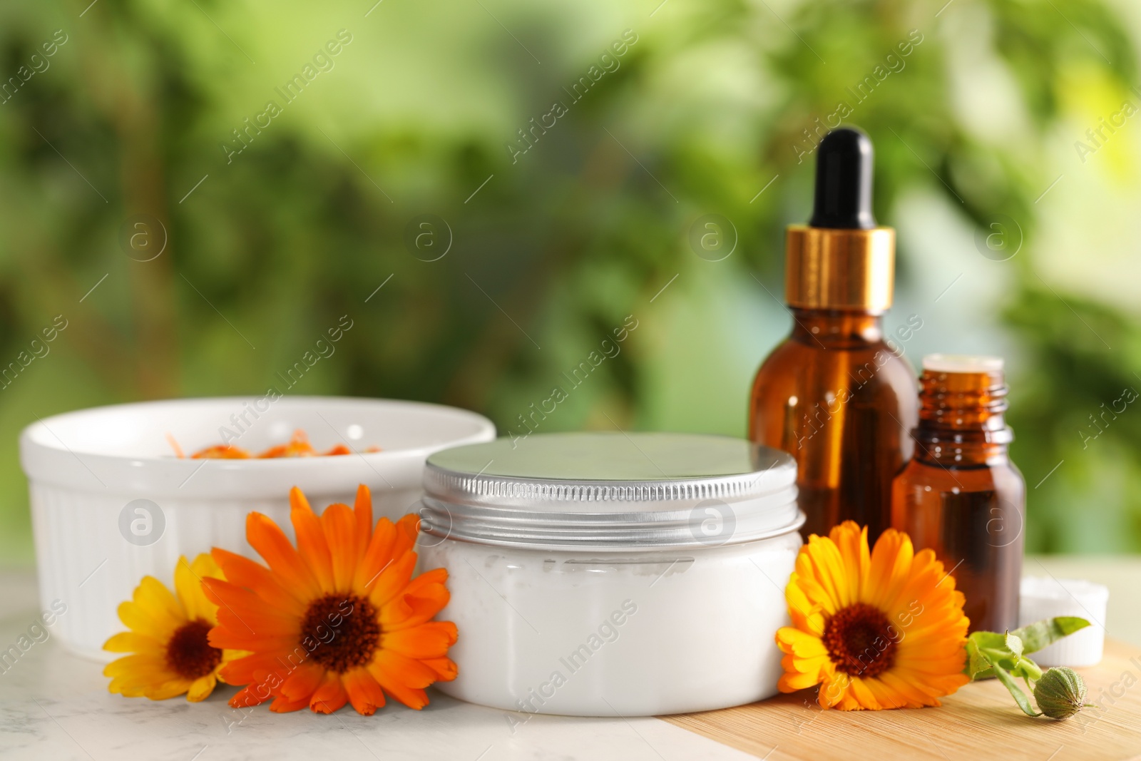 Photo of Different cosmetic products and beautiful calendula flowers on table outdoors, closeup