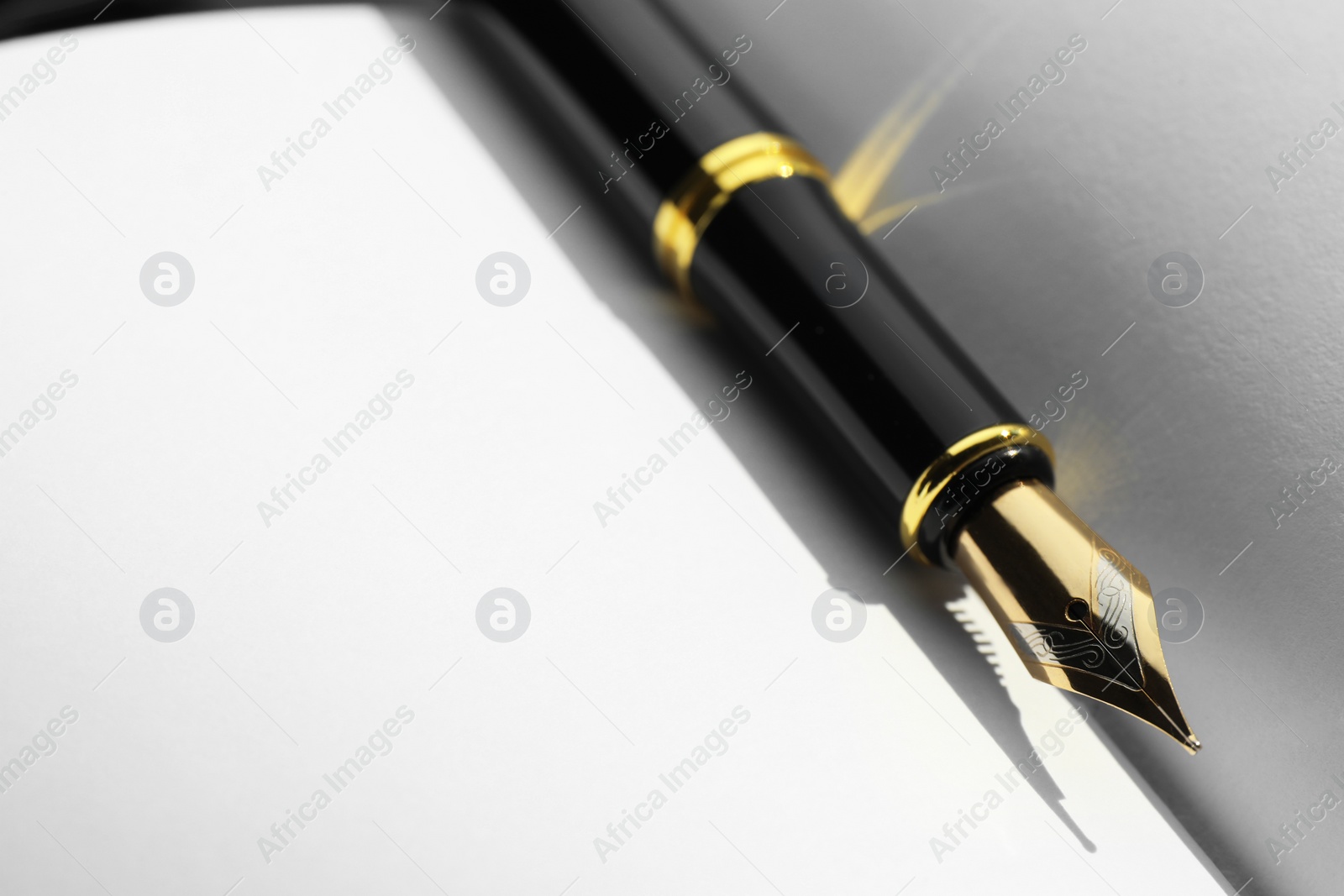 Photo of Stylish black fountain pen on open notebook, closeup. Space for text