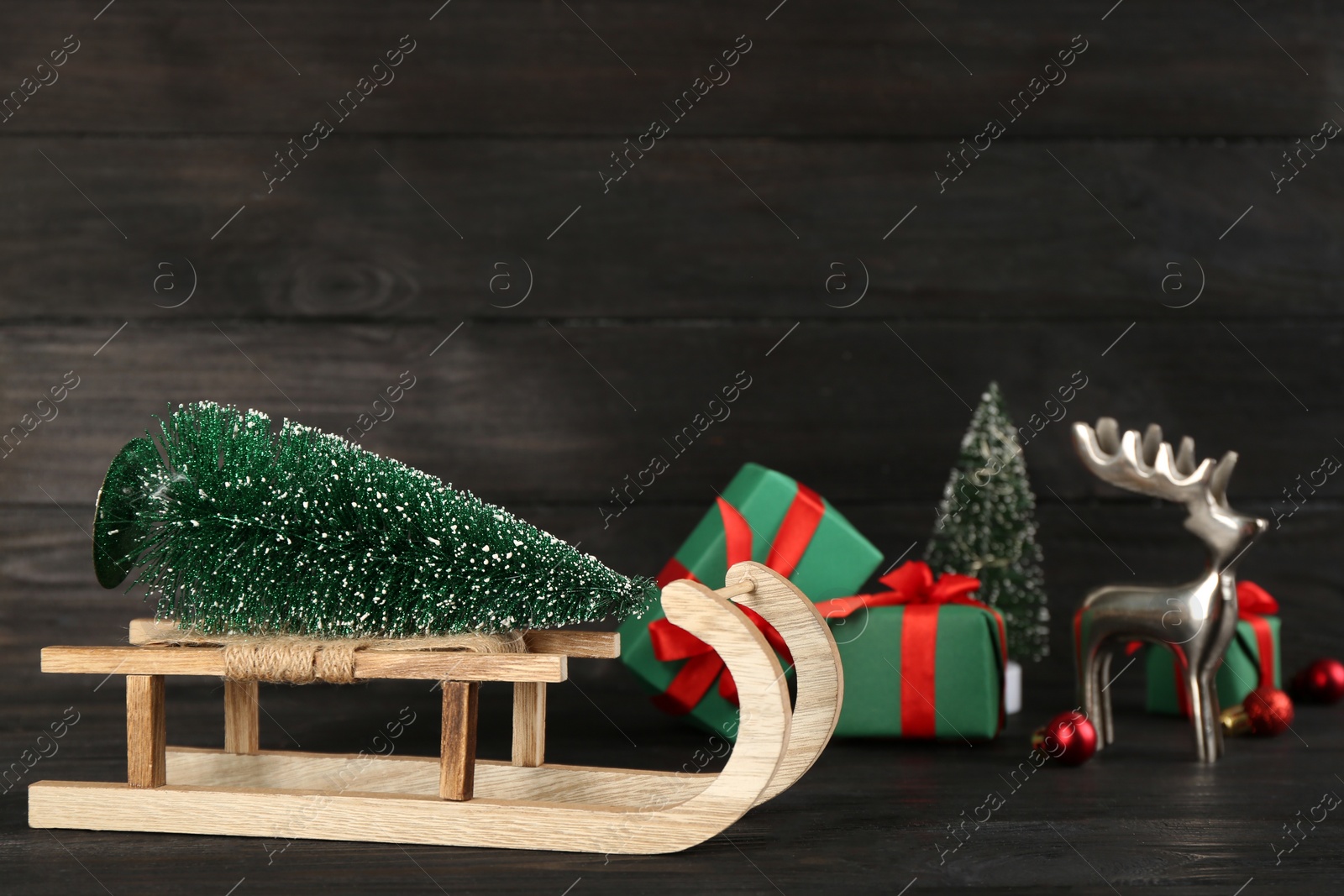 Photo of Beautiful Christmas composition with miniature sleigh on black wooden table. Space for text