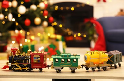 Beautiful toy train on wooden table against blurred festive lights. Christmas celebration