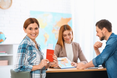 Happy couple choosing tour in travel agency