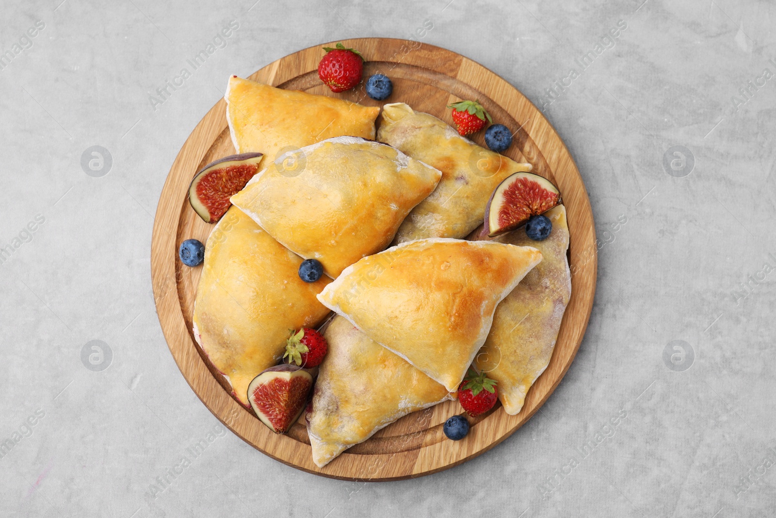Photo of Delicious samosas with figs and berries on grey table, top view