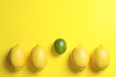 Lime among lemons on yellow background, flat lay. Space for text