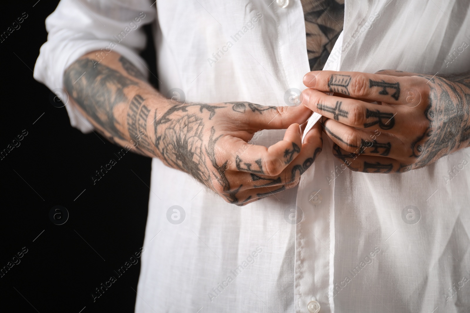 Photo of Young man with tattoos on body against black background, closeup