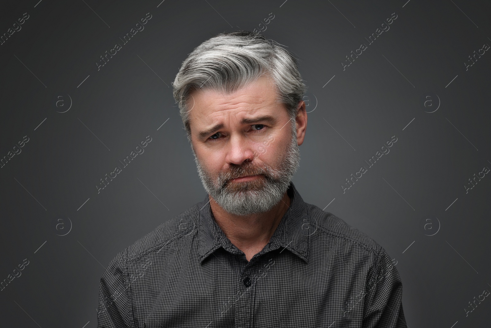 Photo of Personality concept. Portrait of sad man on dark grey background