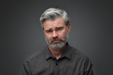Personality concept. Portrait of sad man on dark grey background