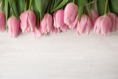 Beautiful pink spring tulips on white wooden background, flat lay. Space for text