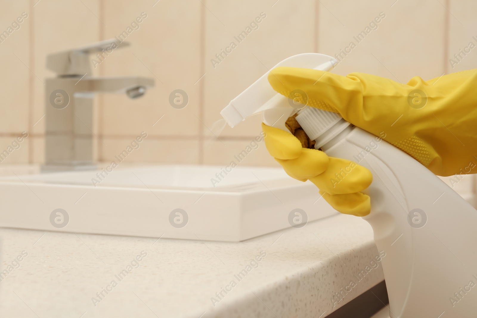 Photo of Person spraying detergent onto counter in bathroom