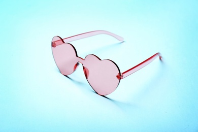 Photo of Stylish heart shaped glasses on color background