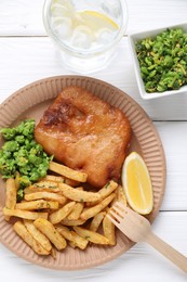 Photo of Tasty fish, chips, peas and lemon on white wooden table, top view