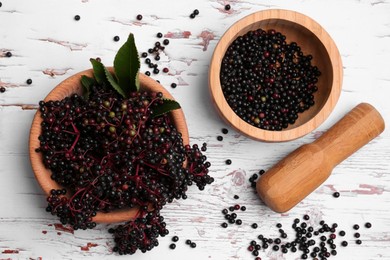 Tasty elderberries (Sambucus) on white wooden table, flat lay