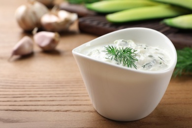 Photo of Cucumber sauce and ingredients on wooden background, space for text. Traditional Tzatziki