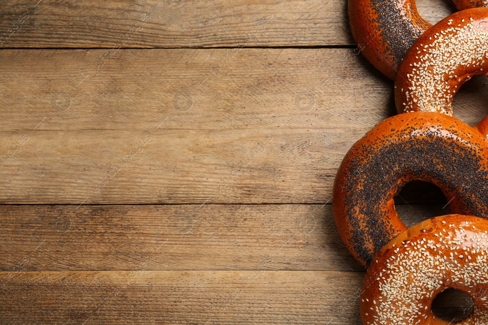 Photo of Many delicious fresh bagels on wooden table, flat lay. Space for text