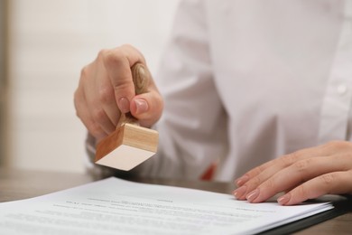 Photo of Woman stamping document at table, closeup view