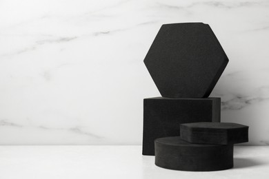 Black geometric figures on white table, space for text. Stylish presentation for product