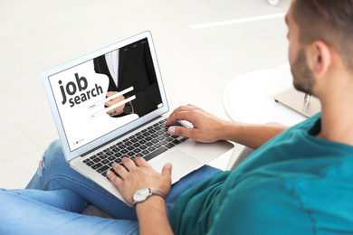 Image of Man searching job with laptop at home 