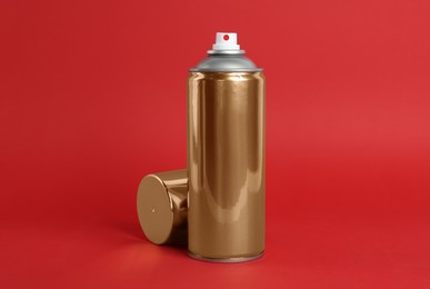 Photo of Golden can of spray paint on red background