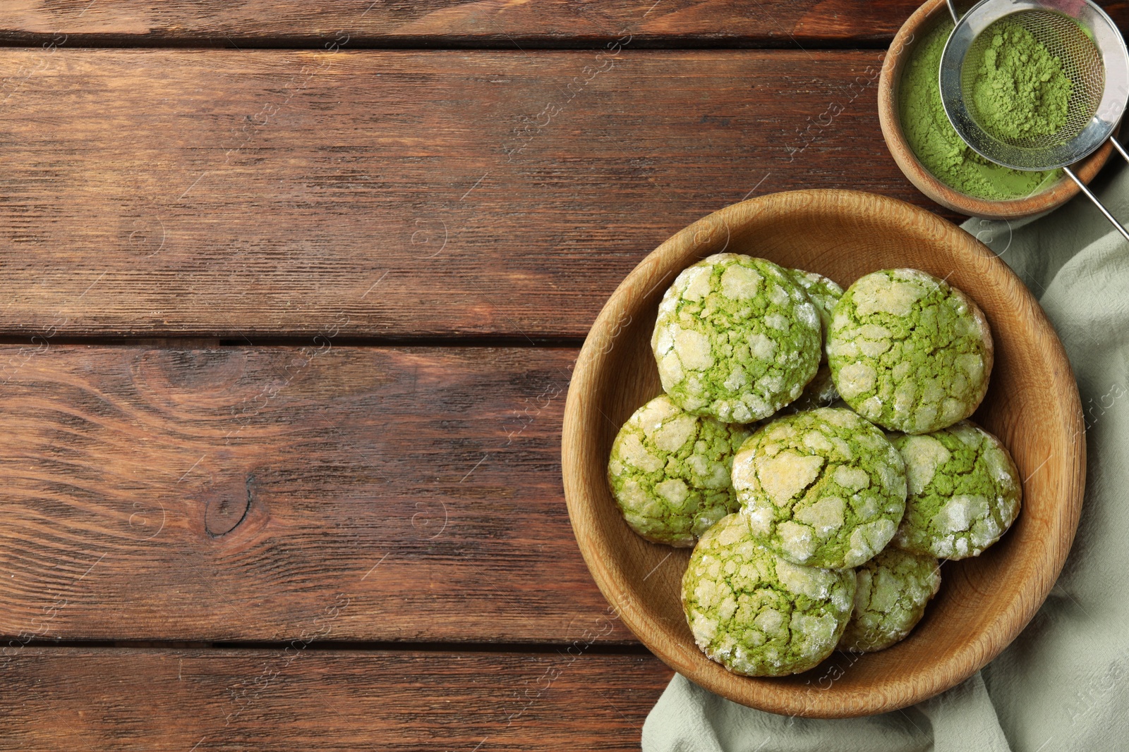 Photo of Bowl with tasty matcha cookies and powder on wooden table, flat lay. Space for text