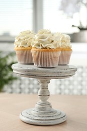 Photo of Tasty cupcakes with vanilla cream on light wooden table