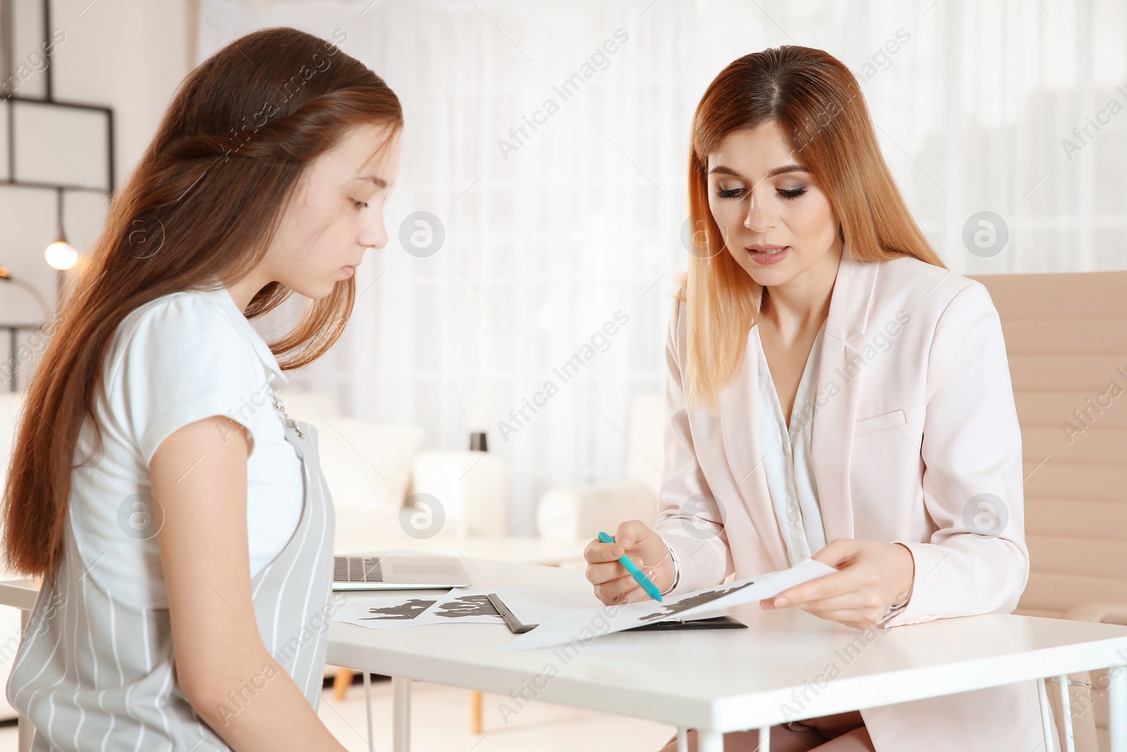 Photo of Female psychologist working with teenager girl in office