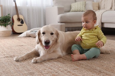 Cute little baby with adorable dog on floor at home