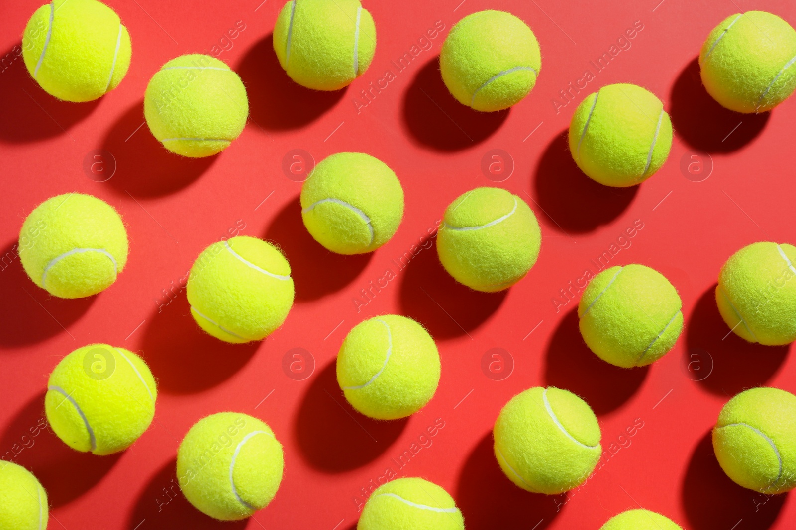Photo of Tennis balls on red background, flat lay. Sports equipment