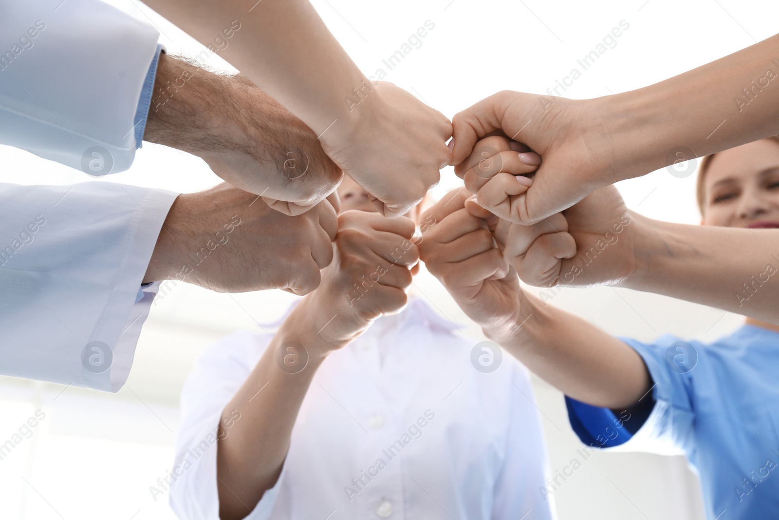 Photo of Team of medical doctors putting hands together on light background, closeup. Unity concept