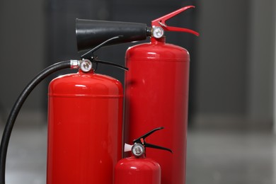 Three new red fire extinguishers in hall, closeup. Space for text