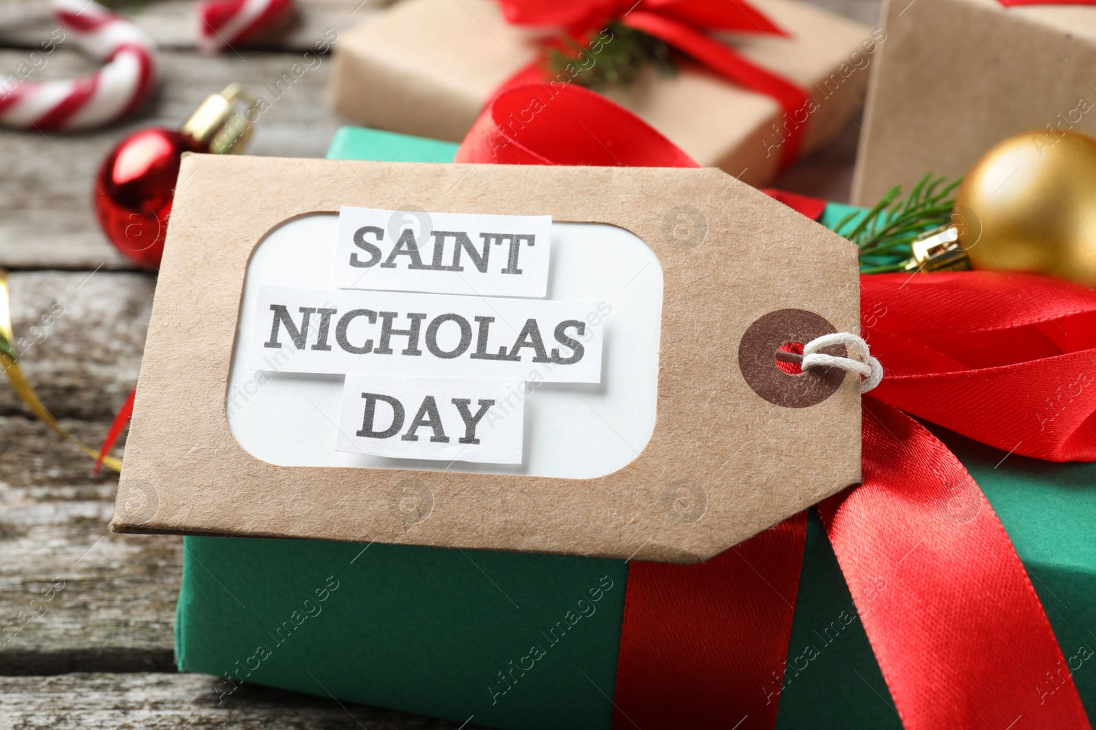 Photo of Saint Nicholas Day. Gift box with tag on wooden table, closeup