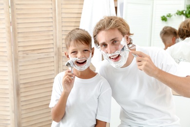 Photo of Father and son shaving together in bathroom