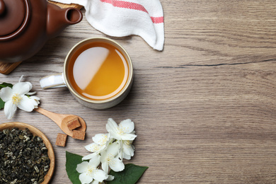 Photo of Flat lay composition with tea and fresh jasmine flowers on wooden table. Space for text