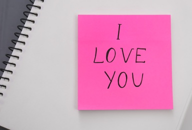 Memory sticker with phrase I Love You on notebook, top view. Valentine's Day celebration