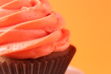 Photo of Delicious cupcake with bright cream on orange background, closeup. Space for text