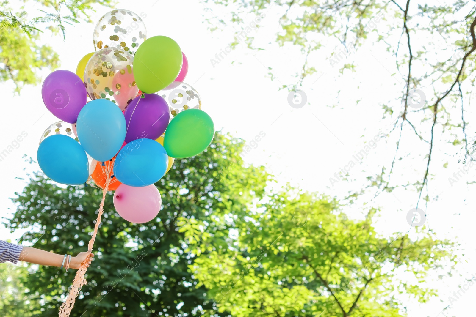 Photo of Young woman with colorful balloons outdoors on sunny day