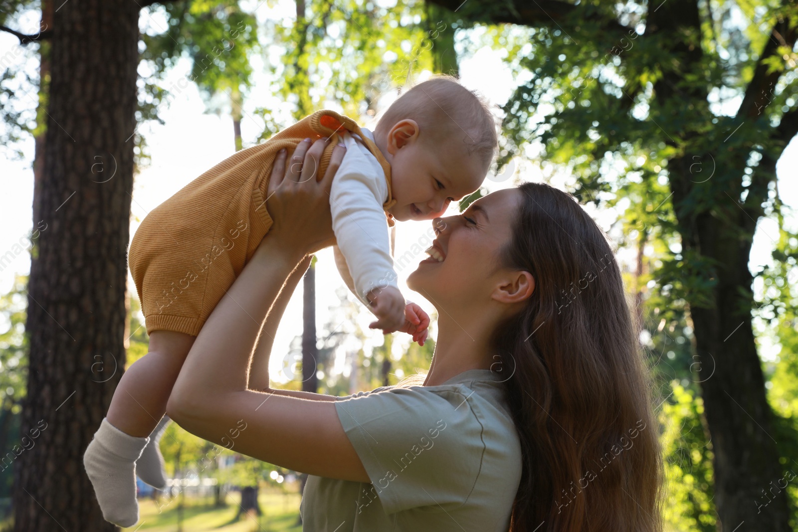 Photo of Beautiful mother with her cute daughter spending time together in park on summer day