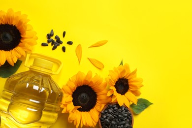 Photo of Bottle of cooking oil, sunflowers and seeds on yellow background, flat lay